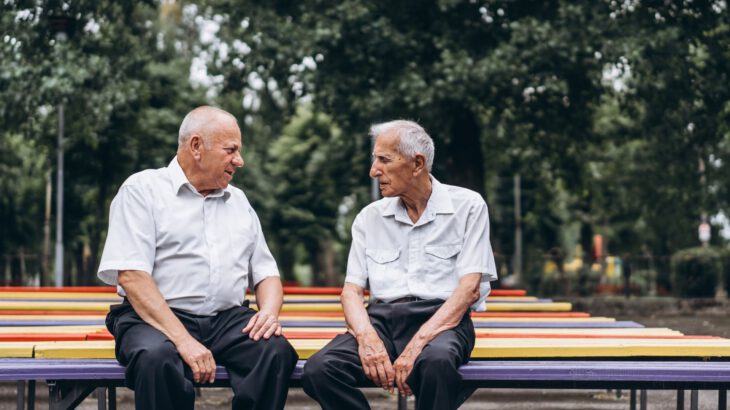 Dwóch starszych mężczyzn siedzi na ławce w parku
